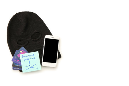 Composition with balaclava, cell phone, credit cards and paper with text INCORRECT PASSWORD on white background. Fraud conceptの写真素材