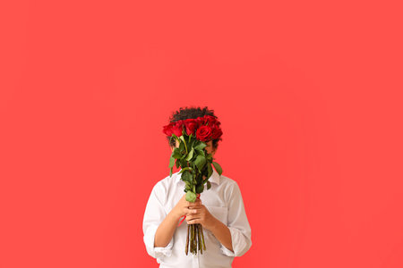 African-American boy with bouquet of beautiful flowers on color backgroundの写真素材