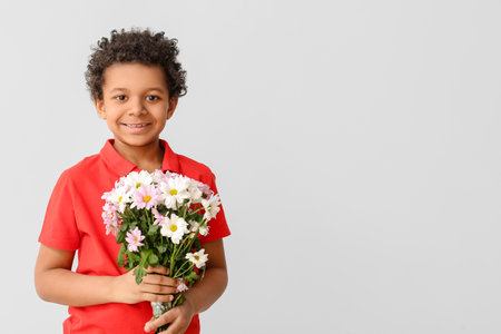 African-American boy with bouquet of beautiful flowers on gray backgroundの写真素材