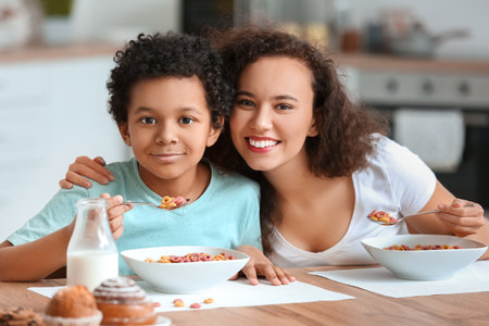Little boy with mother eating cornflakes at home
