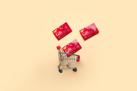Shopping cart with gift cards on color background
