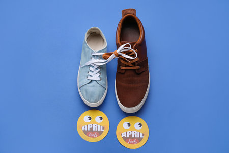 Different shoes with tied laces on color background. April Fool's Day prankの写真素材