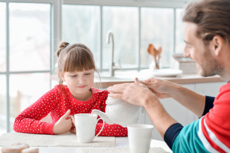 Happy father and daughter having breakfast at homeの写真素材