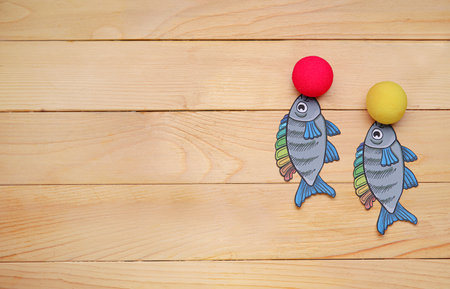 Paper fishes and clown noses on wooden background. April Fools Day celebrationの写真素材