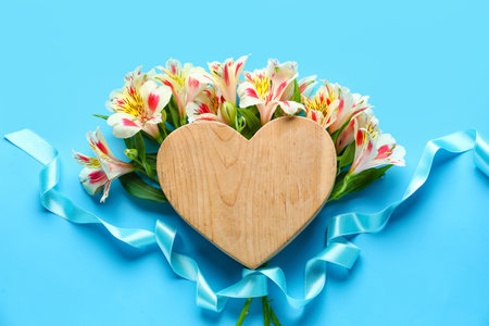 Composition with bouquet of beautiful alstroemeria flowers and wooden heart on color background. mother's day celebrationの写真素材