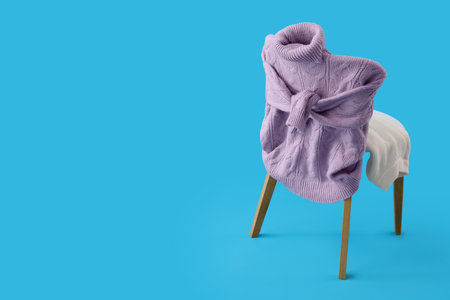 Chair with knitted sweaters on blue backgroundの写真素材