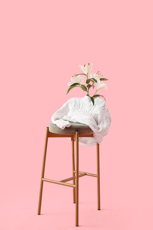 Stool with white sweater and lily flowers on pink backgroundの写真素材