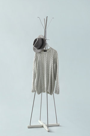Rack with sweater and hat on gray background