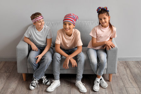 Happy little friends sitting on sofa near gray wallの写真素材