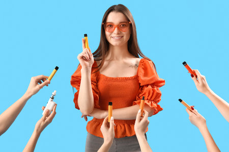 Young woman and hands with disposable electronic cigarettes on blue backgroundの写真素材