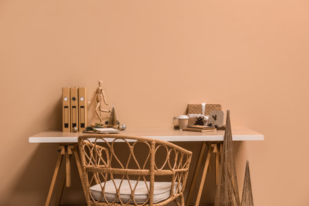 Workplace with Christmas decor, gift, coffee cup and mannequin near beige wallの写真素材