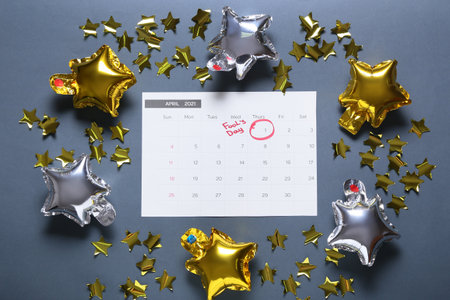 Calendar with marked date of April Fool's Day and party decor on gray backgroundの写真素材