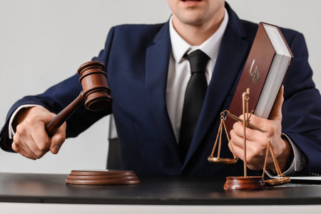Male judge at table on gray background
