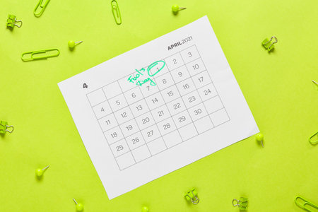 Calendar with marked date of April Fool's Day and stationery on color background