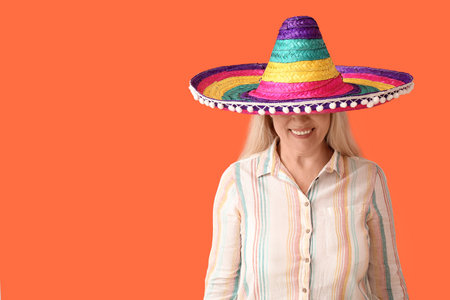 Mature Mexican woman in sombrero hat on color background
