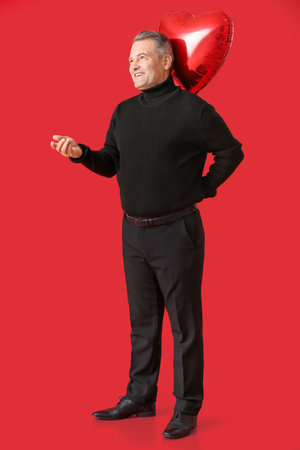 Mature man with balloon on color background. Valentine's Day celebrationの写真素材