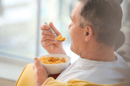 Senior man eating cornflakes at homeの写真素材