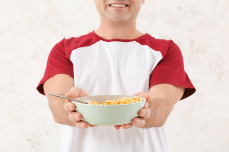 Senior man and bowl with cornflakes on white backgroundの写真素材