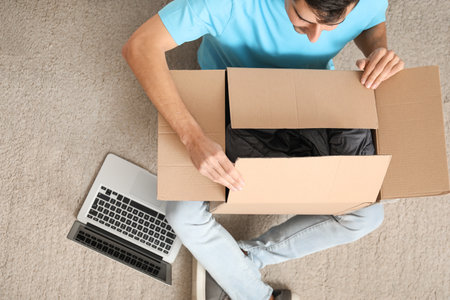 Handsome young man unpacking box at home
