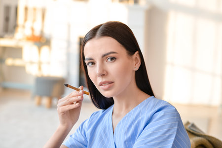 Young woman smoking cigarette at homeの写真素材