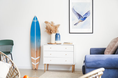 Interior of modern stylish room with chest of drawers, sofa and surfboardの写真素材