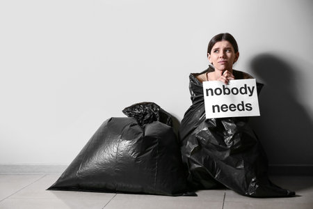 Young woman with garbage bags near light wall. concept of abandoned animalsの写真素材
