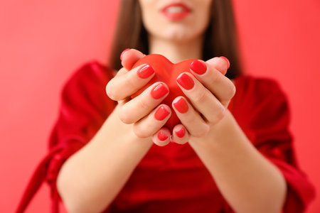 Young woman with beautiful manicure and red heart on color background, closeupの写真素材