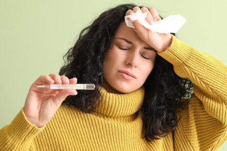 Sick young woman with thermometer on color background