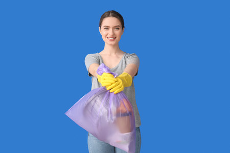 Young woman with garbage bag on color backgroundの写真素材
