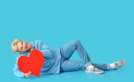 Cute man with big red heart on color backgroundの写真素材