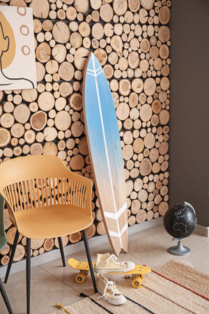 Interior of modern stylish room with surfboard and chair near wooden wallの写真素材