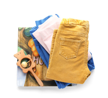 Child's pants, rattle and book on white backgroundの写真素材