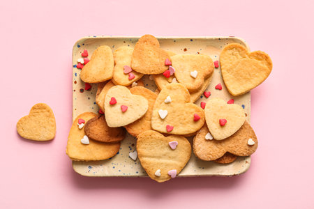 Plate with sweet heart shaped cookies and sprinkles on pink background. valentine's day celebrationの写真素材