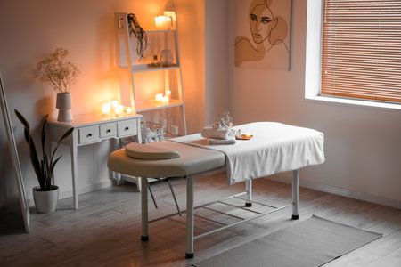 Interior of spa salon with couch, shelving unit and burning candlesの写真素材