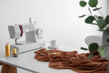 Tailor's workplace with sewing machine and cloth in light atelier