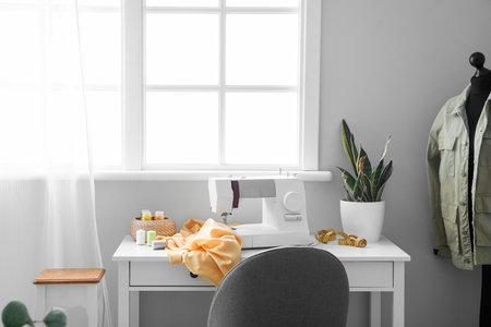 Tailor's workplace with sewing machine and houseplant near windowの写真素材