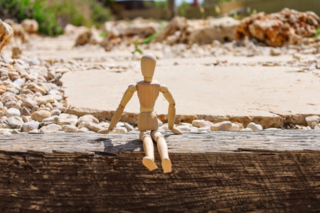Wooden mannequin sitting on wooden edge in park, closeupの写真素材