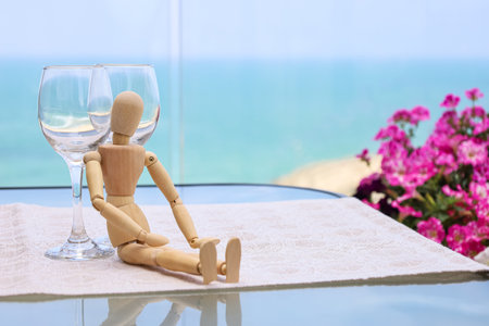 Wooden mannequin with wine glasses on tableの写真素材