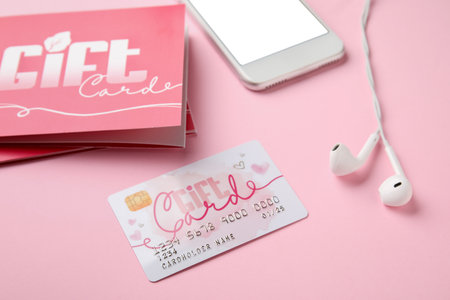 Gift card and mobile phone on color background, closeup