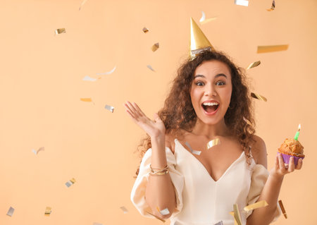 Happy African-American woman celebrating Birthday against color backgroundの写真素材