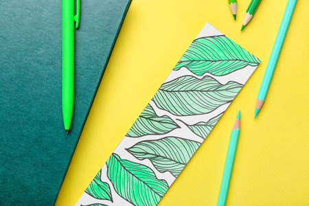 Cute bookmark with book and stationery on color background