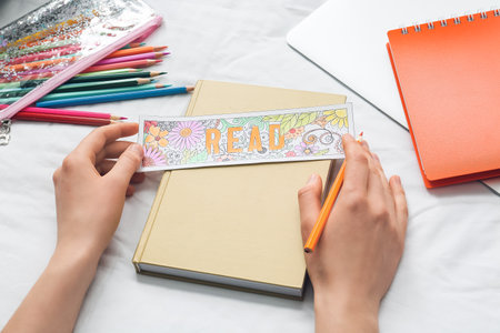 Woman coloring bookmark on bedの写真素材