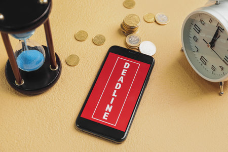 Mobile phone with hourglass and alarm clock on color background. Dead line conceptの写真素材