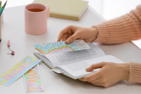 Woman with cute bookmarks and book at tableの写真素材