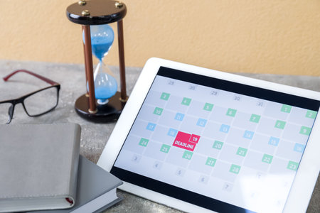 Tablet computer and hour glass on grunge background. Dead line conceptの写真素材