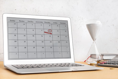 Hourglass and laptop with calendar on light background. Dead line conceptの写真素材