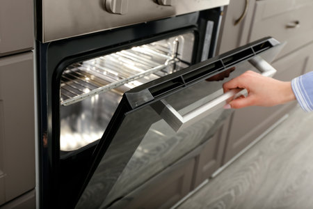 Woman opening oven in kitchenの写真素材