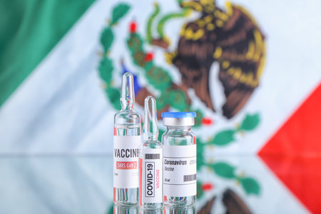 COVID-19 vaccine on table against flag of Mexicoの写真素材