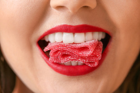 Beautiful young woman with sweet candy in mouth, closeupの写真素材
