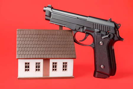 Model of house and gun on color background. concept of hostageの写真素材